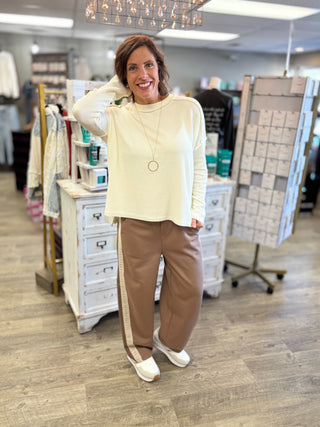 Model wearing a cream ribbed top with mocha pants featuring a cream lace detail.