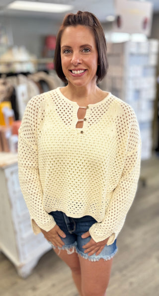 Woman wearing a cream sweater and denim shorts in an indoor setting