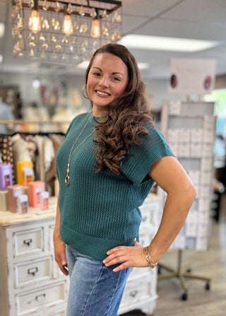Model wearing teal green sweater with denim jeans