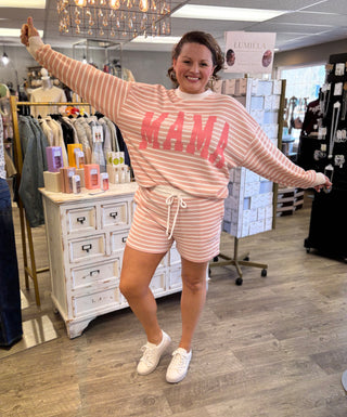 Woman wearing a pink 'MAMA' outfit in a store setting