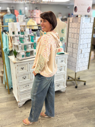 Model wearing oatmeal and floral printed lightweight hoodie and jeans in a store