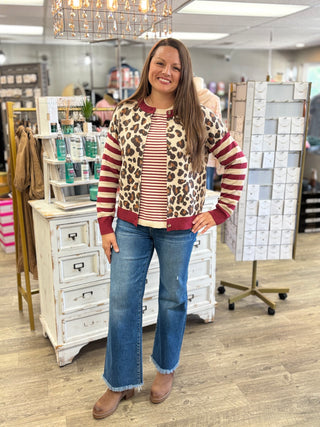 Model wearing a cream and burgundy striped sweater with a leopard print, burgundy and cream striped sweater, jeans and boots.