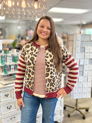 Model wearing a cream and burgundy striped sweater with a leopard print, burgundy and cream striped cardigan and jeans.