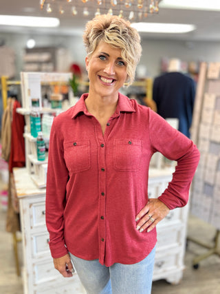 Front view of a heather red button-up top with a pointed collar, long sleeves, and two chest pockets.
