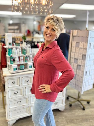 Side view of a model wearing a heather red long-sleeve button-up top with a relaxed silhouette and curved hem.