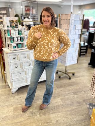 Model wearing a fawn printed sweater, jeans, and boots.