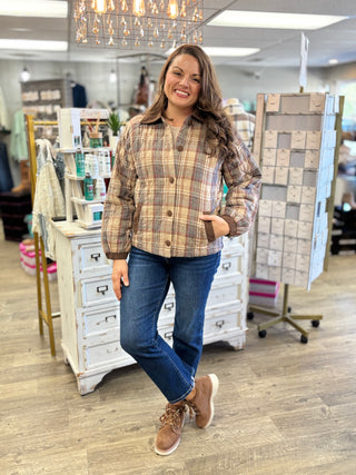 Model wearing a multi brown plaid quilted barn jacket with corduroy collar and buttons, jeans, and boots.